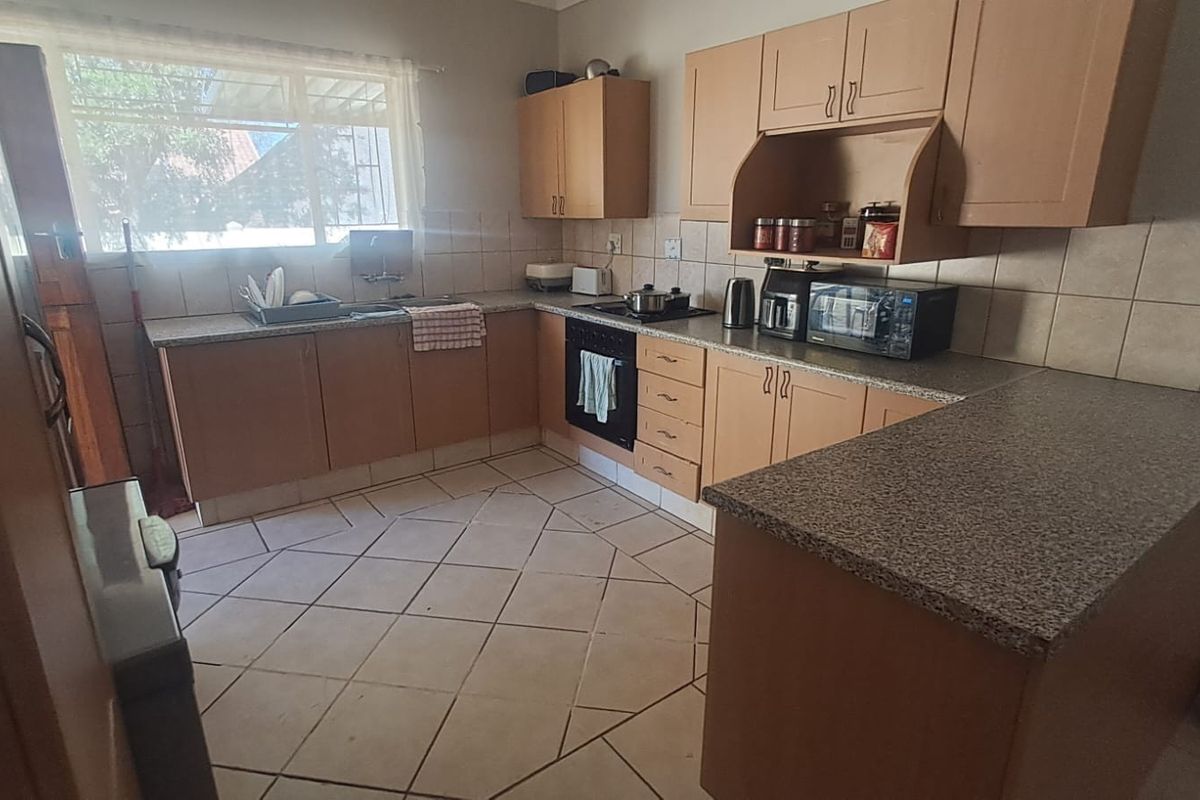 A functional kitchen featuring laminate cabinetry, granite countertops, a built-in oven, and tiled flooring, offering a practical layout with ample workspace.