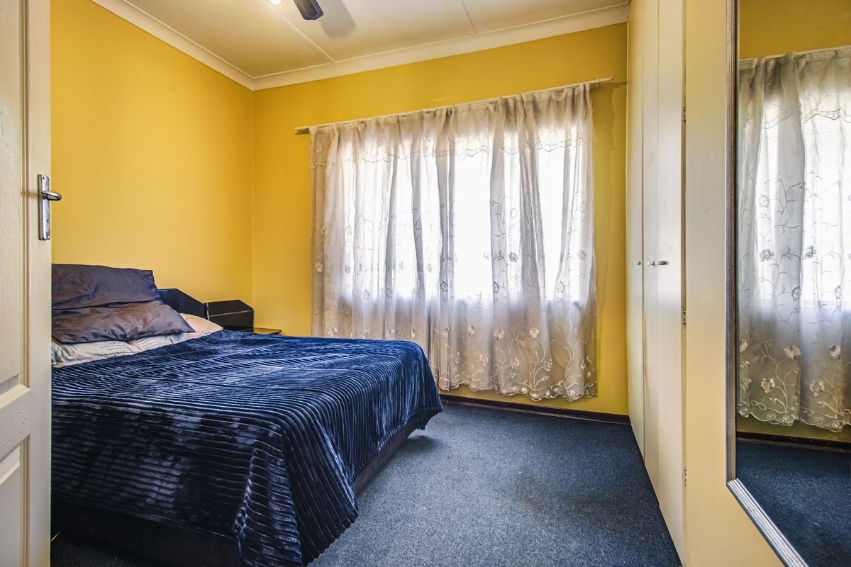 A bedroom featuring built-in cupboards, a ceiling fan, and carpeted flooring, providing a functional space with potential for cosmetic updates.