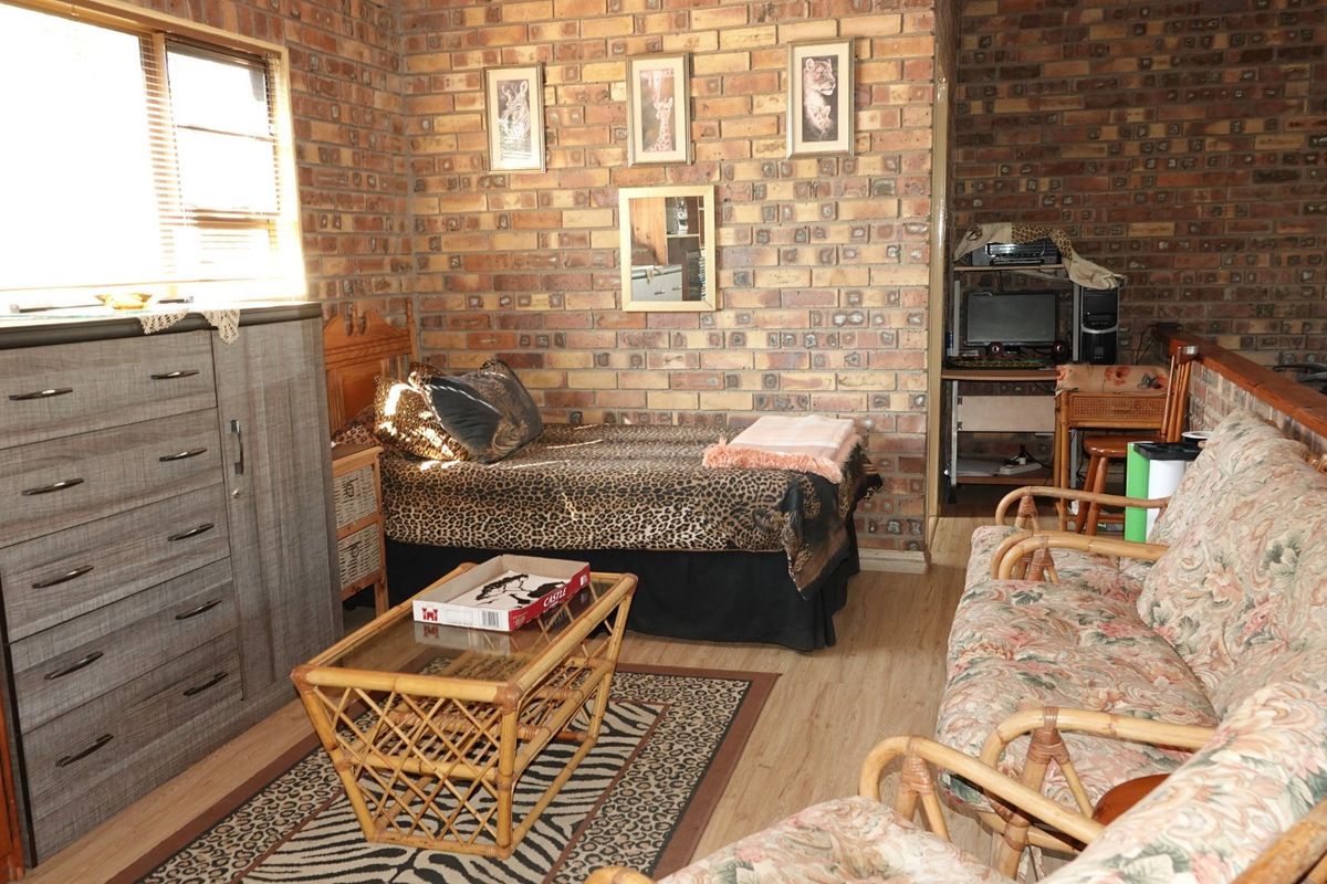 A bedroom featuring exposed brick walls and laminate flooring, offering a rustic aesthetic with natural light from the window.