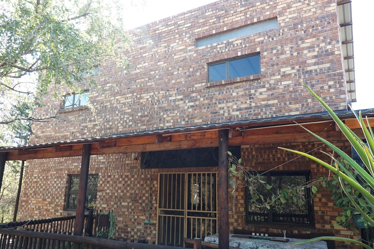 A rear view of a double-story face brick house featuring a covered timber veranda and security entrance.