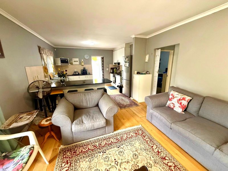 Open-plan living and kitchen area featuring hardwood flooring, a breakfast bar island, and functional kitchen cabinetry with built-in appliances.