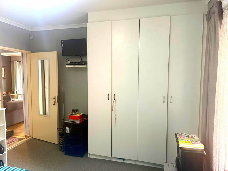 A bedroom featuring a large white built-in wardrobe and an internal door with an integrated mirror.
