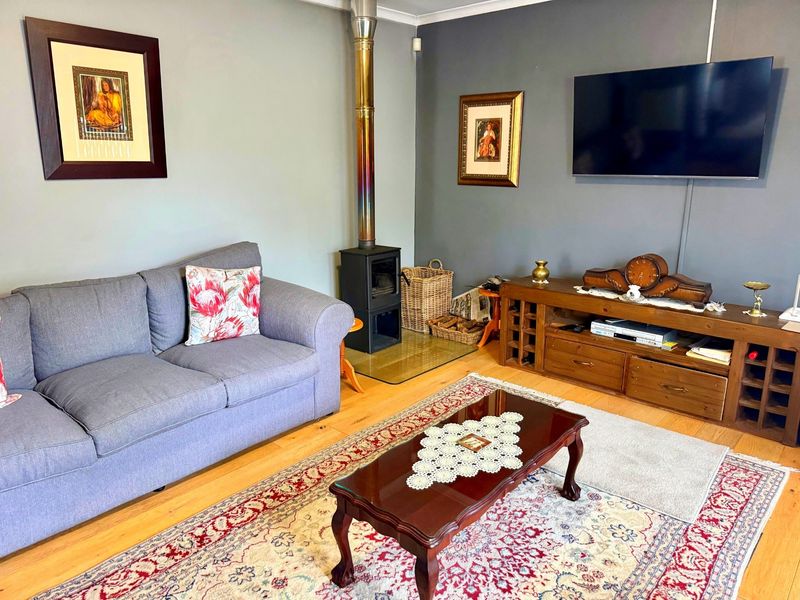 A cozy living room featuring hardwood flooring and a built-in wood-burning stove with a stainless steel flue pipe.