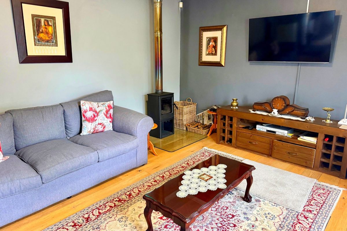 A cozy living room featuring hardwood flooring and a built-in wood-burning stove with a stainless steel flue pipe.