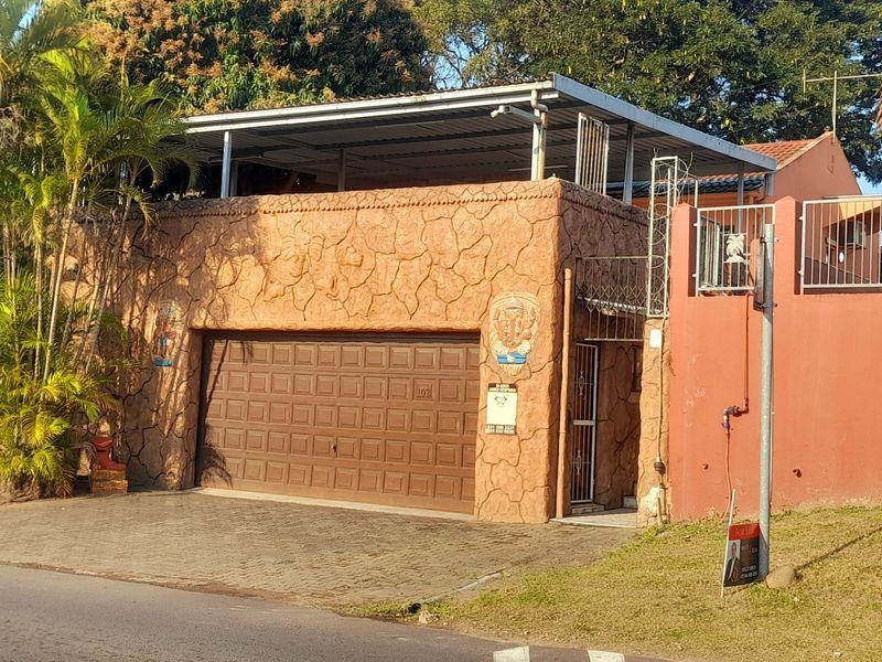 Front exterior view of the property featuring a garage with a textured facade, paved driveway, and perimeter security fencing.