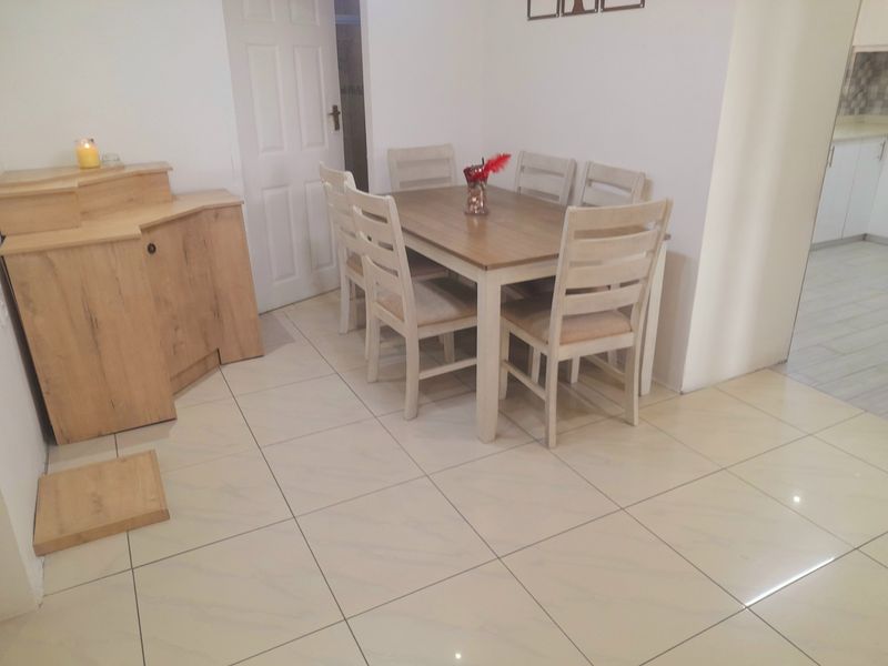A dining area featuring light-colored floor tiles and neutral wall finishes, providing a clean and functional space for meals.