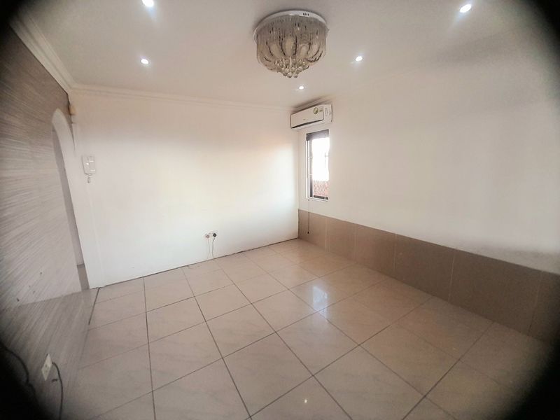 An empty living room featuring tiled flooring, a split-system air conditioner, and recessed lighting, offering a clean, neutral space ready for personalization.