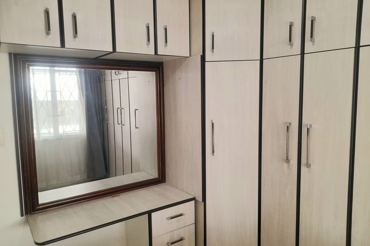 Bedroom featuring extensive built-in cabinetry with a central vanity area and integrated mirror, providing ample storage space.