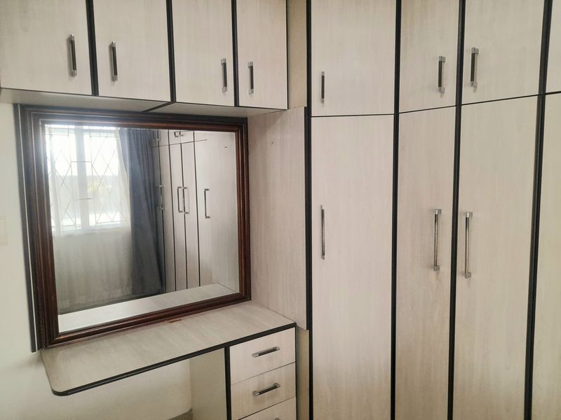 Bedroom featuring extensive built-in cabinetry with a central vanity area and integrated mirror, providing ample storage space.