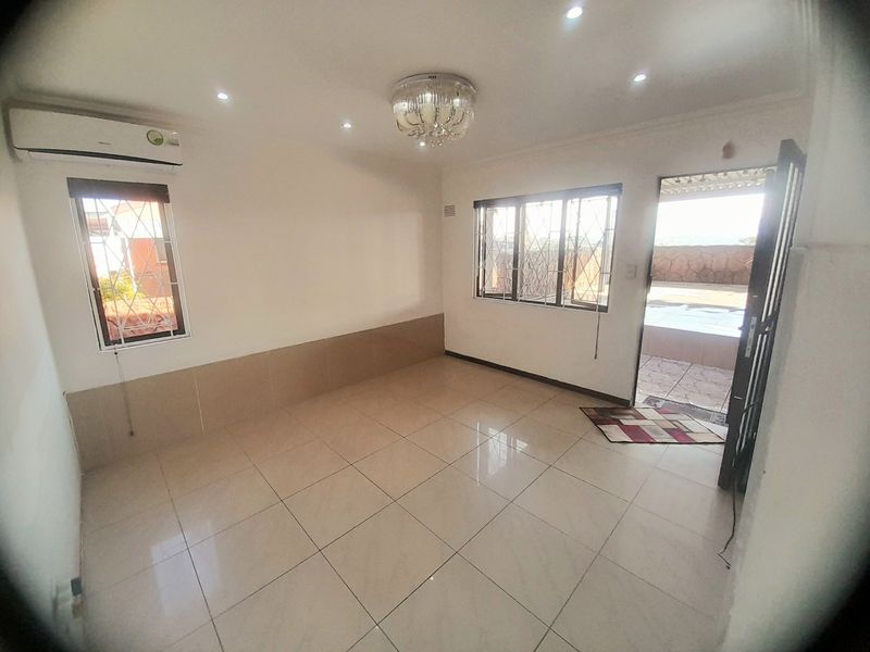 A bright, empty living area featuring tiled flooring, recessed lighting, a split-system air conditioner, and direct access to an outdoor patio area.