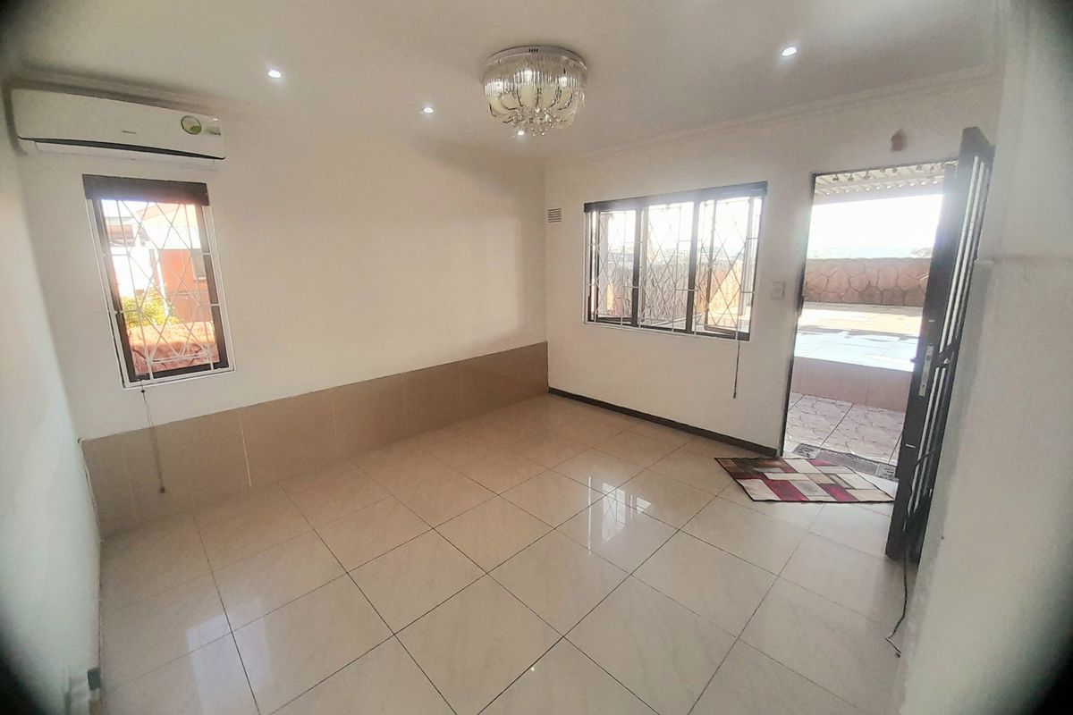 A bright, empty living area featuring tiled flooring, recessed lighting, a split-system air conditioner, and direct access to an outdoor patio area.