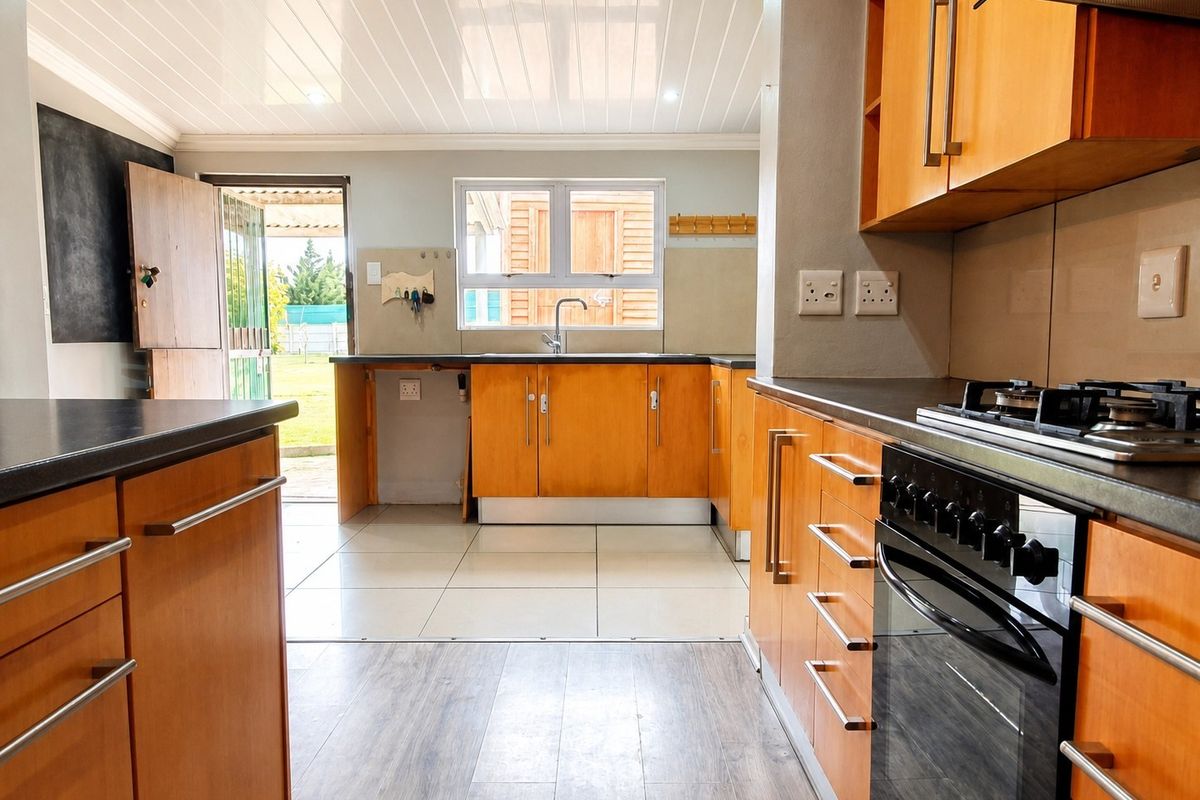 Functional kitchen featuring wooden cabinetry, gas hob, built-in oven, and direct access to the rear garden area.