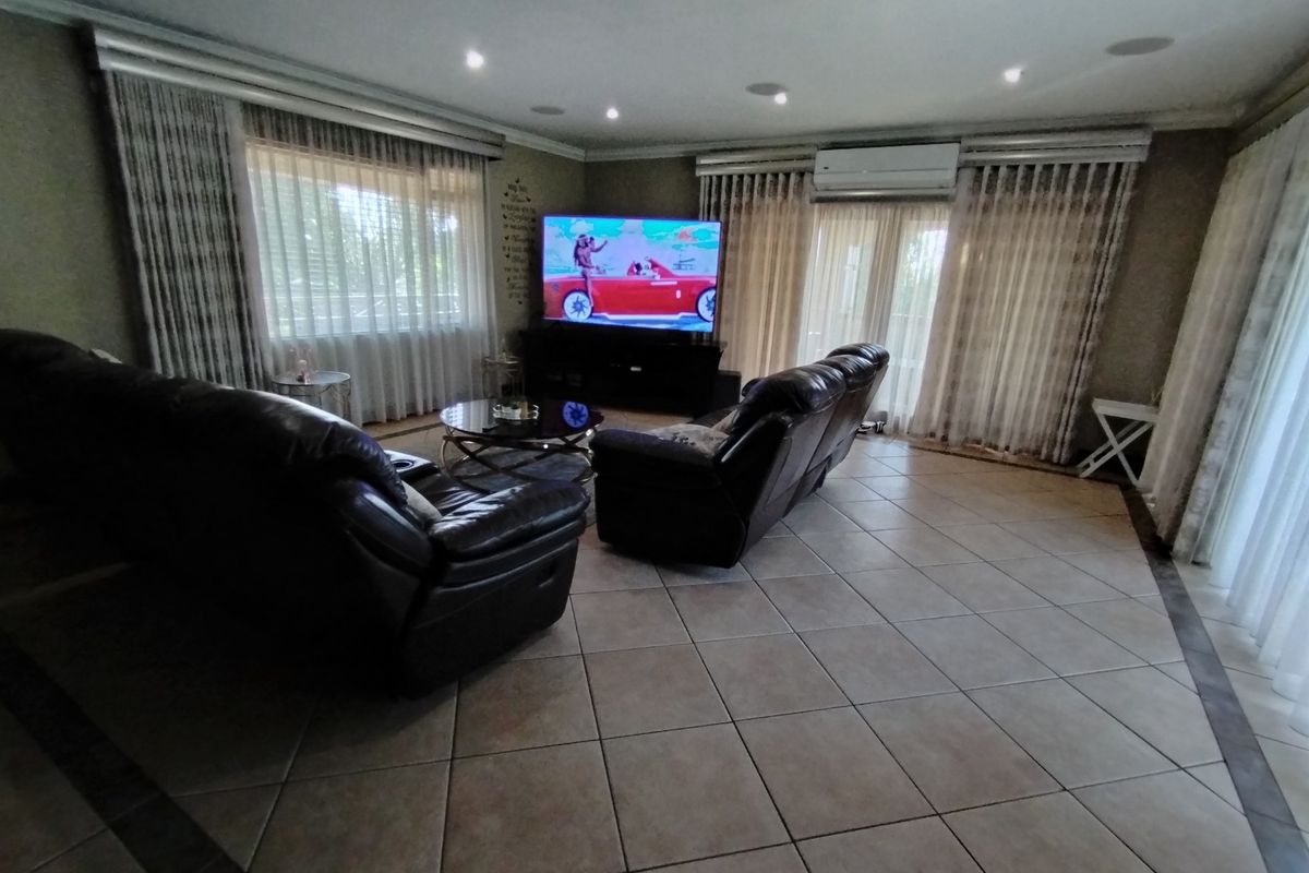 Spacious living room featuring tiled flooring, recessed downlighting, integrated ceiling speakers, and a wall-mounted split-system air conditioner.
