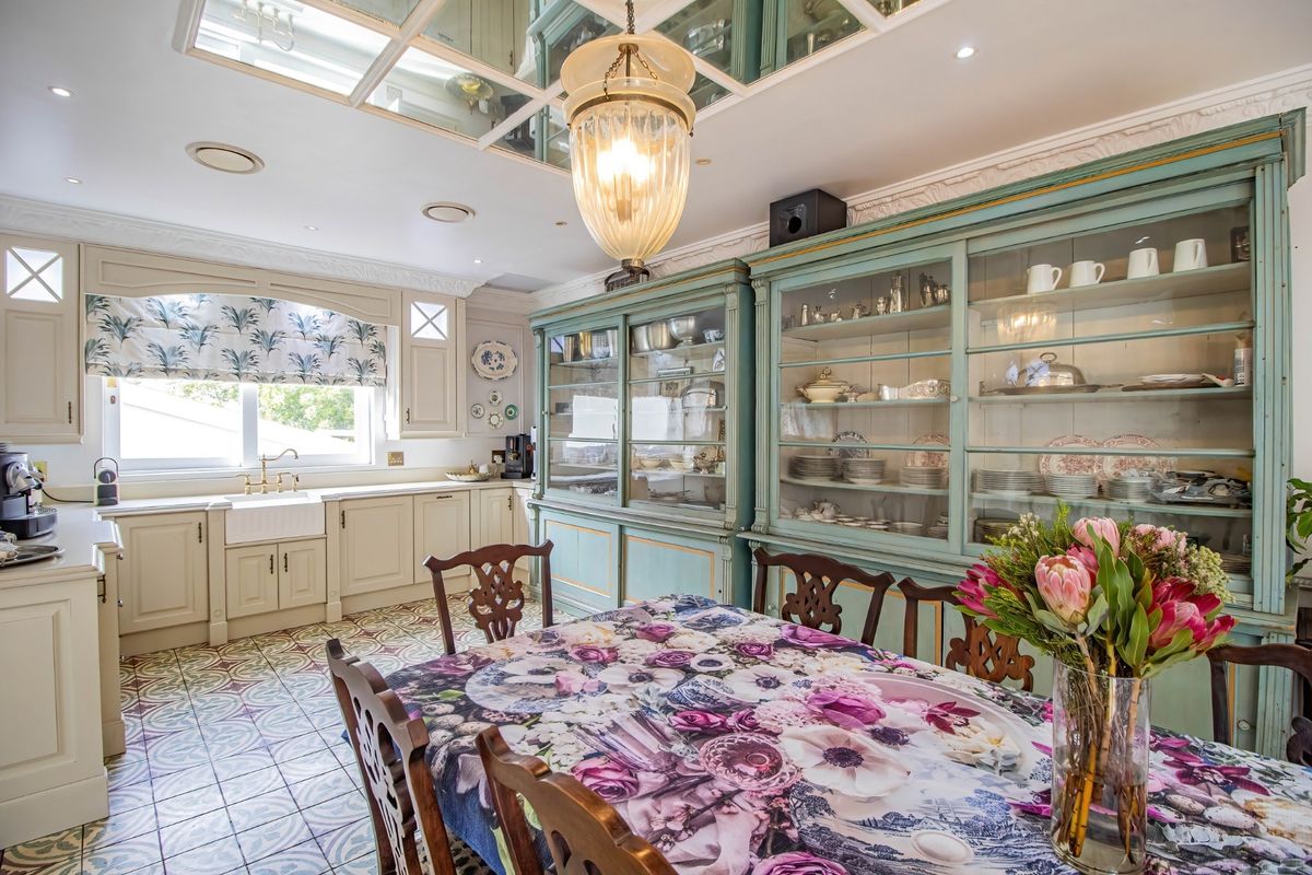 A well-appointed kitchen featuring classic farmhouse sink, extensive built-in cabinetry, decorative patterned floor tiles, and a unique mirrored ceiling detail.