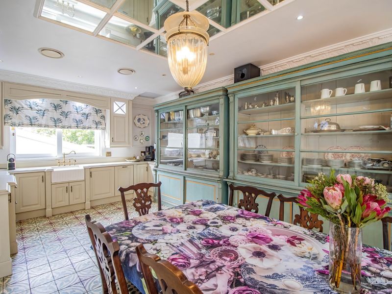 A well-appointed kitchen featuring classic farmhouse sink, extensive built-in cabinetry, decorative patterned floor tiles, and a unique mirrored ceiling detail.