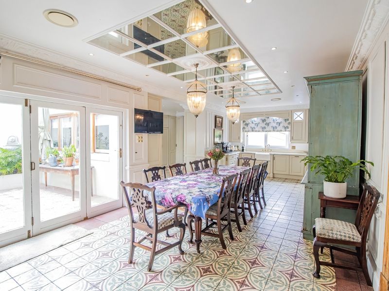 Spacious open-plan dining and kitchen area featuring decorative patterned floor tiles, a unique mirrored ceiling feature, and direct access to an outdoor patio.