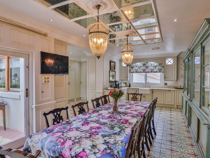 Spacious open-plan kitchen and dining area featuring a unique mirrored ceiling, patterned floor tiles, custom cabinetry, and an elegant apron front sink.
