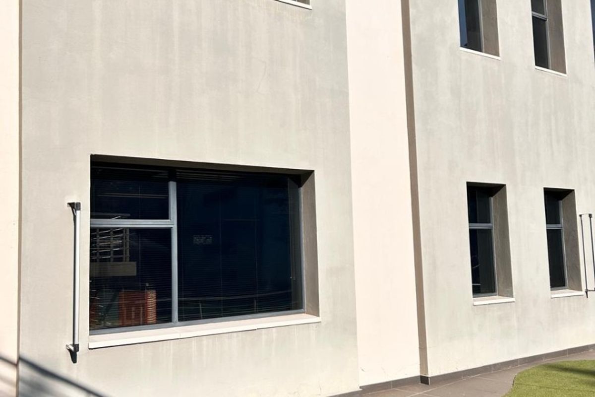 Rear exterior view of a commercial building featuring a paved patio area, artificial lawn, and modern aluminium-framed windows.