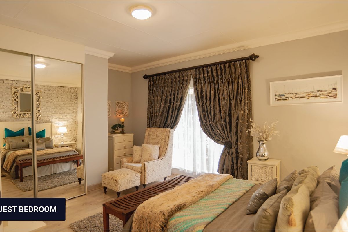 A well-maintained guest bedroom featuring a built-in mirrored wardrobe, an exposed brick feature wall, and elegant cove cornicing.