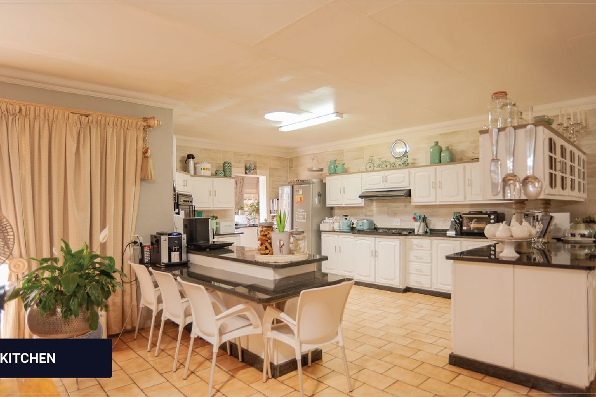 Spacious kitchen featuring white cabinetry, granite countertops, a central breakfast bar, and tiled flooring, offering a functional layout for family living.