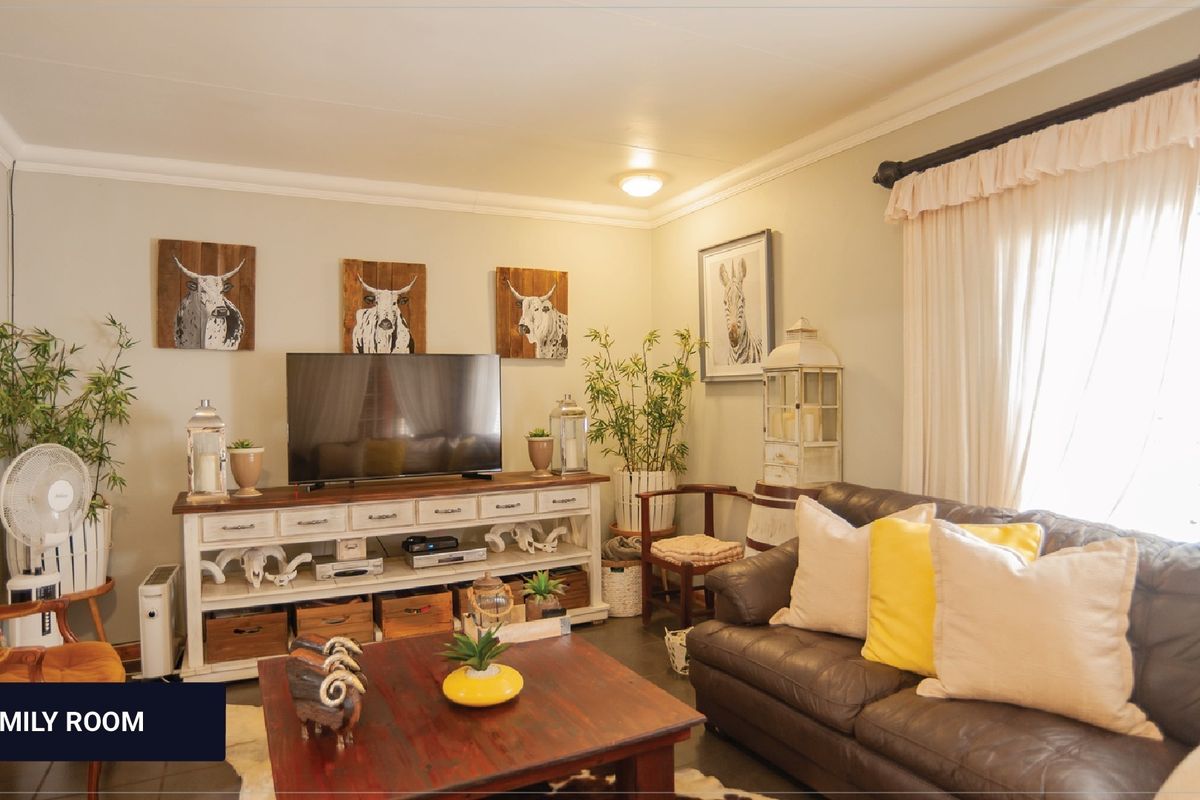 A comfortable living room featuring crown molding, tiled flooring, and neutral wall tones, providing a cozy and well-maintained space for relaxation.
