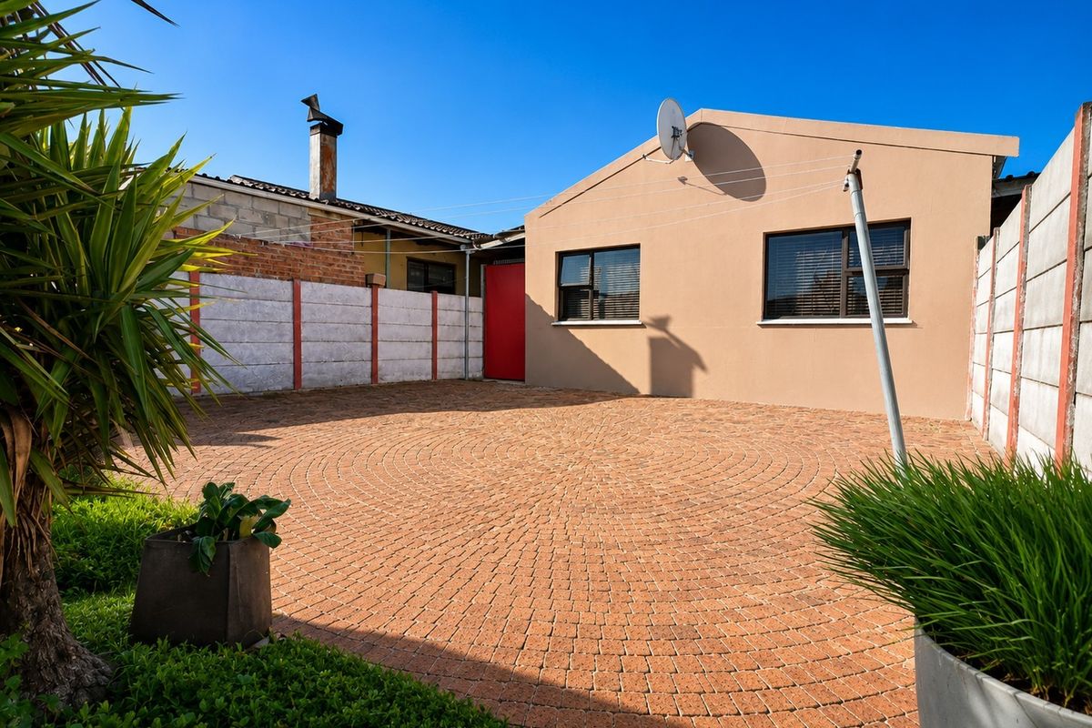 A private rear courtyard featuring circular patterned paving, enclosed by precast concrete boundary walls and a solid exterior facade.