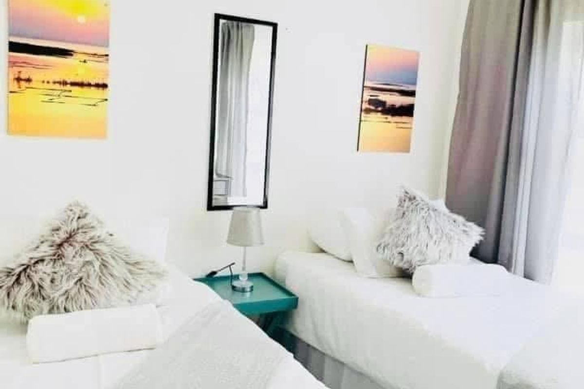 A bedroom featuring neutral wall finishes and window treatments, providing a functional space for sleeping arrangements.