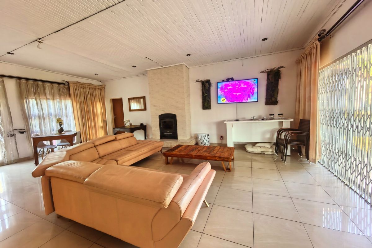 Spacious living room featuring tiled flooring, a central fireplace, and a timber-clad ceiling, offering a comfortable area for relaxation and family gatherings.
