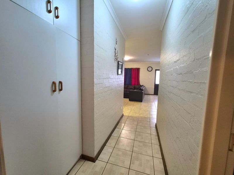 A functional hallway featuring built-in storage cabinetry, tiled flooring, and painted brick walls, leading through to the main living area.