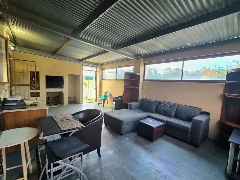Spacious living area featuring a corrugated metal ceiling, concrete flooring, and a built-in fireplace, offering a rustic industrial aesthetic.