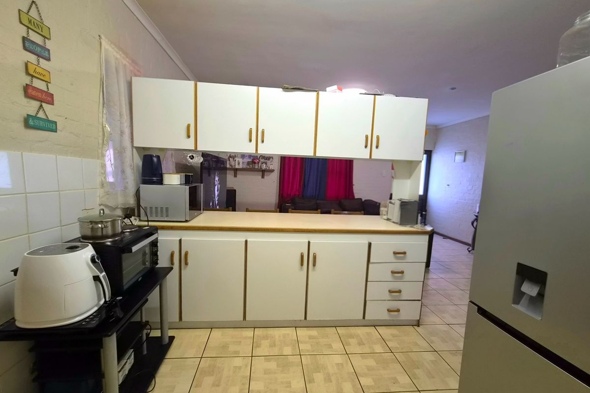 A functional kitchen featuring white cabinetry, laminate countertops, and tiled flooring, offering a dated aesthetic with potential for modern renovation.