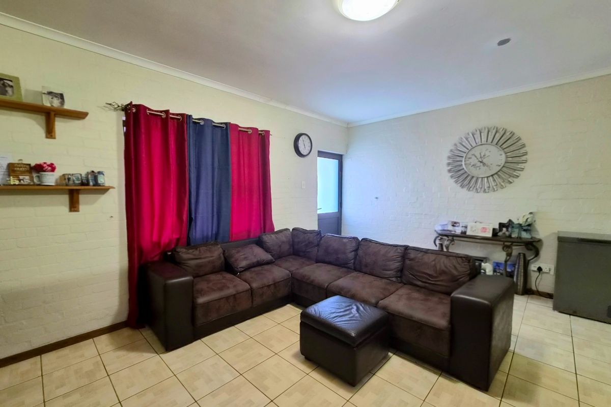 A living room featuring painted brick walls, ceramic tiled flooring, and a flush mount ceiling light fixture.