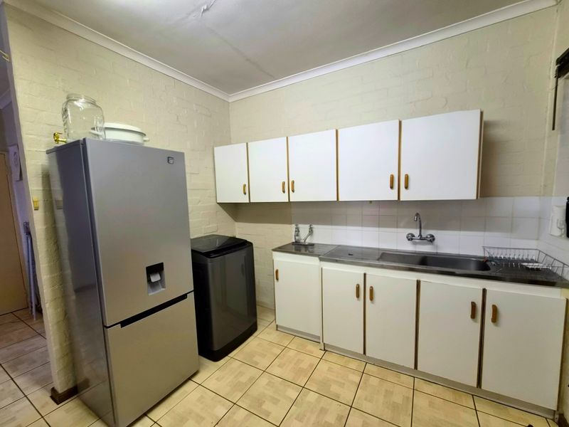 A functional scullery area featuring built-in cabinetry, a stainless steel sink, and tiled finishes, providing practical utility space for the home.