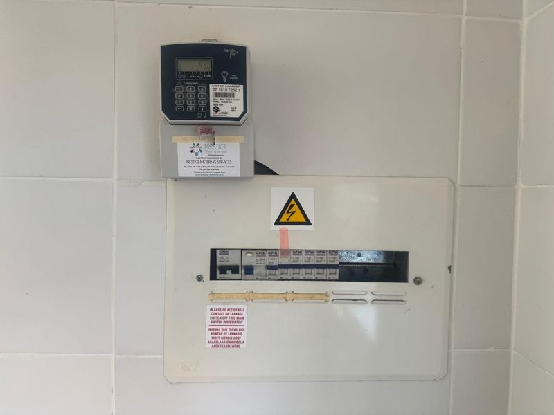 A wall-mounted electrical distribution board featuring a prepaid electricity meter and a series of circuit breakers.