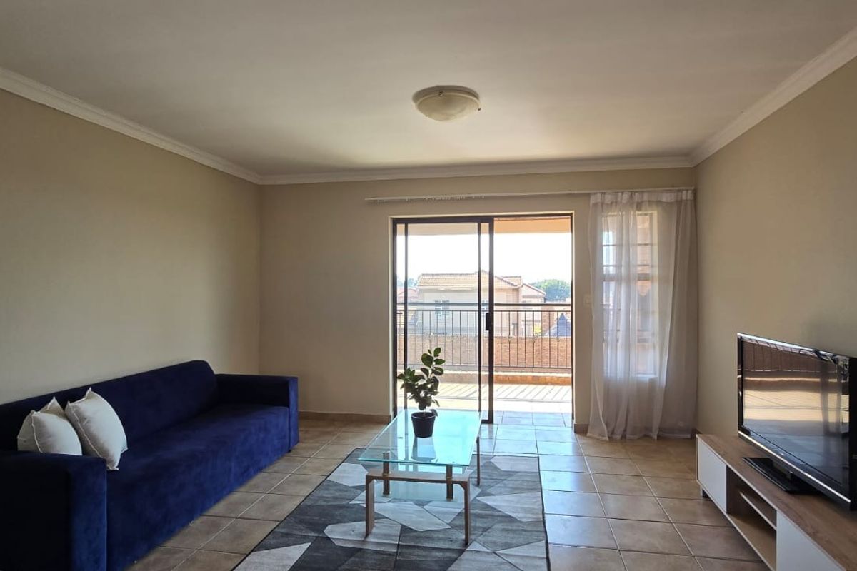 A well-lit living room featuring tiled flooring and a sliding glass door that provides access to an outdoor balcony area.