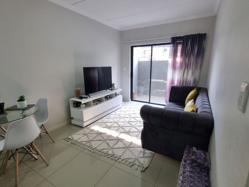A bright living room featuring tiled flooring and a sliding glass door providing access to an outdoor area.