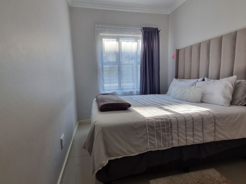 A well-maintained bedroom featuring neutral wall tones, tiled flooring, and a coved ceiling, providing a clean and comfortable living space.