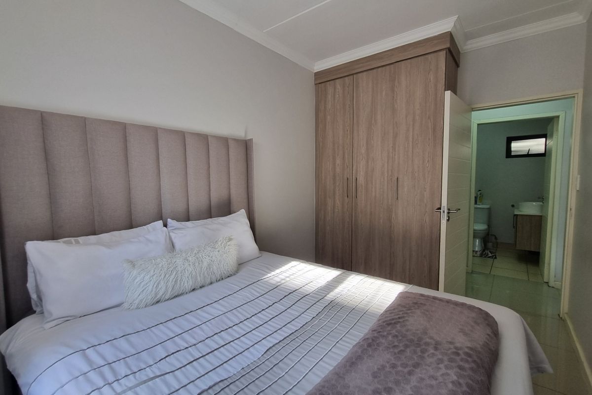 A well-maintained bedroom featuring built-in cupboards, neutral wall finishes, and direct access to an en-suite bathroom.