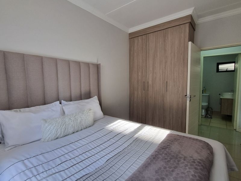 A well-maintained bedroom featuring built-in cupboards, neutral wall finishes, and direct access to an en-suite bathroom.