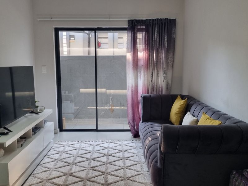 A cozy living room featuring tiled flooring and a large sliding glass door that provides access to the outdoor area.