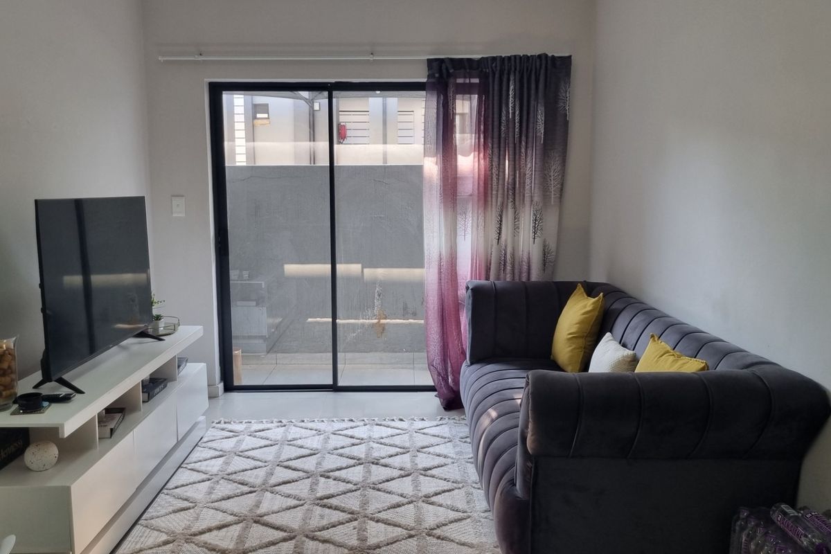A cozy living room featuring tiled flooring and a large sliding glass door that provides access to the outdoor area.