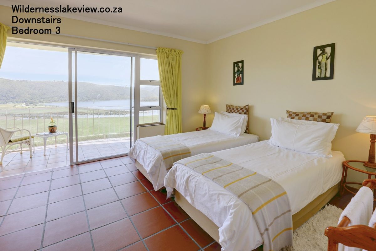 Bedroom featuring tiled flooring and large sliding glass doors opening onto a balcony with scenic lake views.