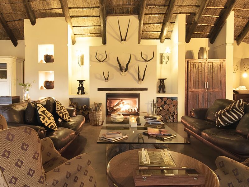 Spacious living room featuring a high thatched roof with exposed timber rafters, a central built-in fireplace, and integrated wall niches.
