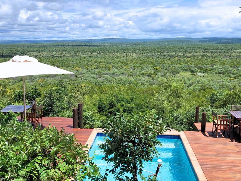 An elevated timber deck featuring a swimming pool with expansive, uninterrupted views over the surrounding natural bushveld landscape.