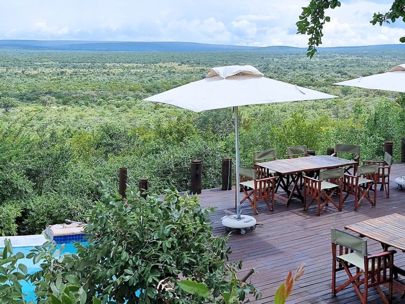 Expansive timber deck patio featuring a swimming pool and panoramic views of the surrounding bushveld landscape.