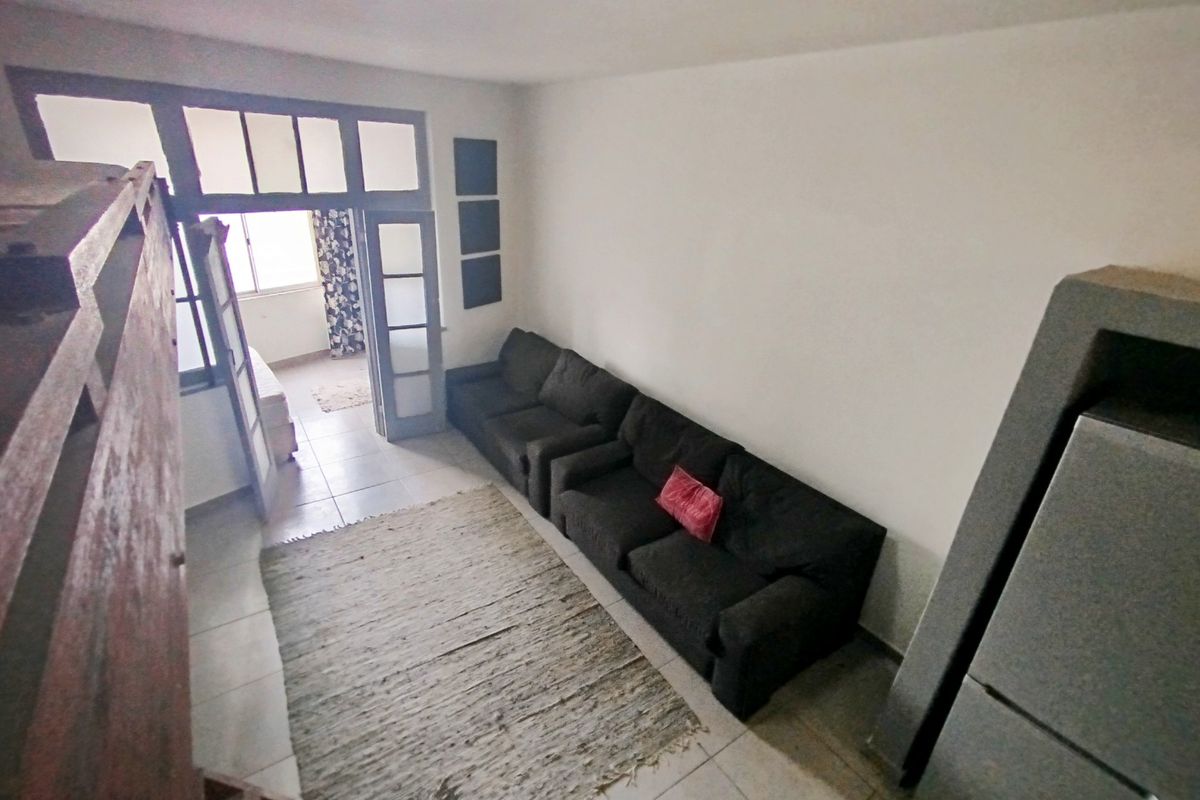 A living room area featuring tiled flooring and a multi-pane glass door leading to an adjacent space, with neutral walls and basic lighting.