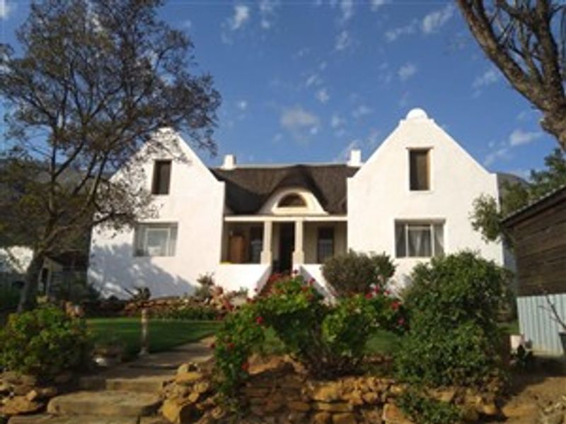 Charming farmhouse featuring a traditional gabled facade, thatched roof, and a stone-walled garden entrance.