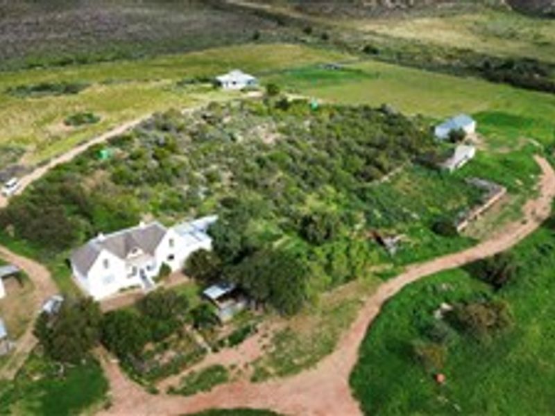 Aerial view of a rural farm property featuring a main farmhouse, multiple outbuildings, and surrounding agricultural land with dirt access tracks.