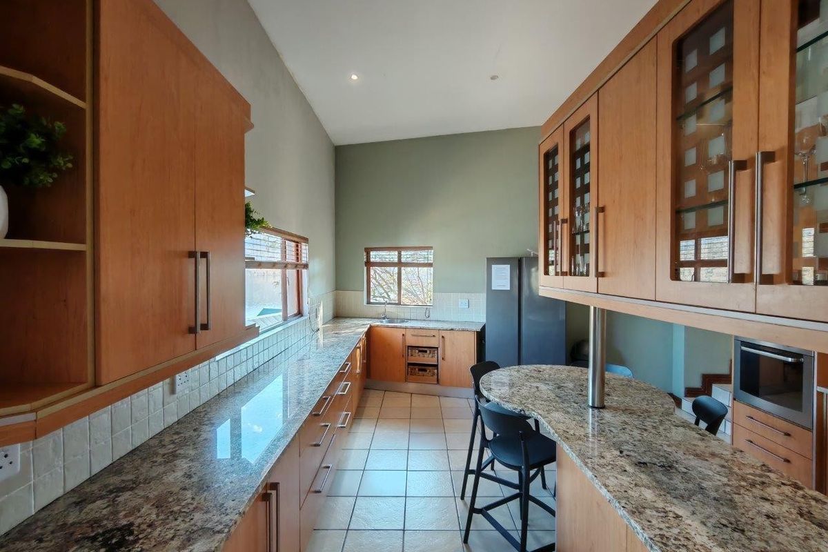 A functional kitchen featuring granite countertops, extensive wooden cabinetry, a breakfast bar, and tiled flooring with integrated built-in appliances.