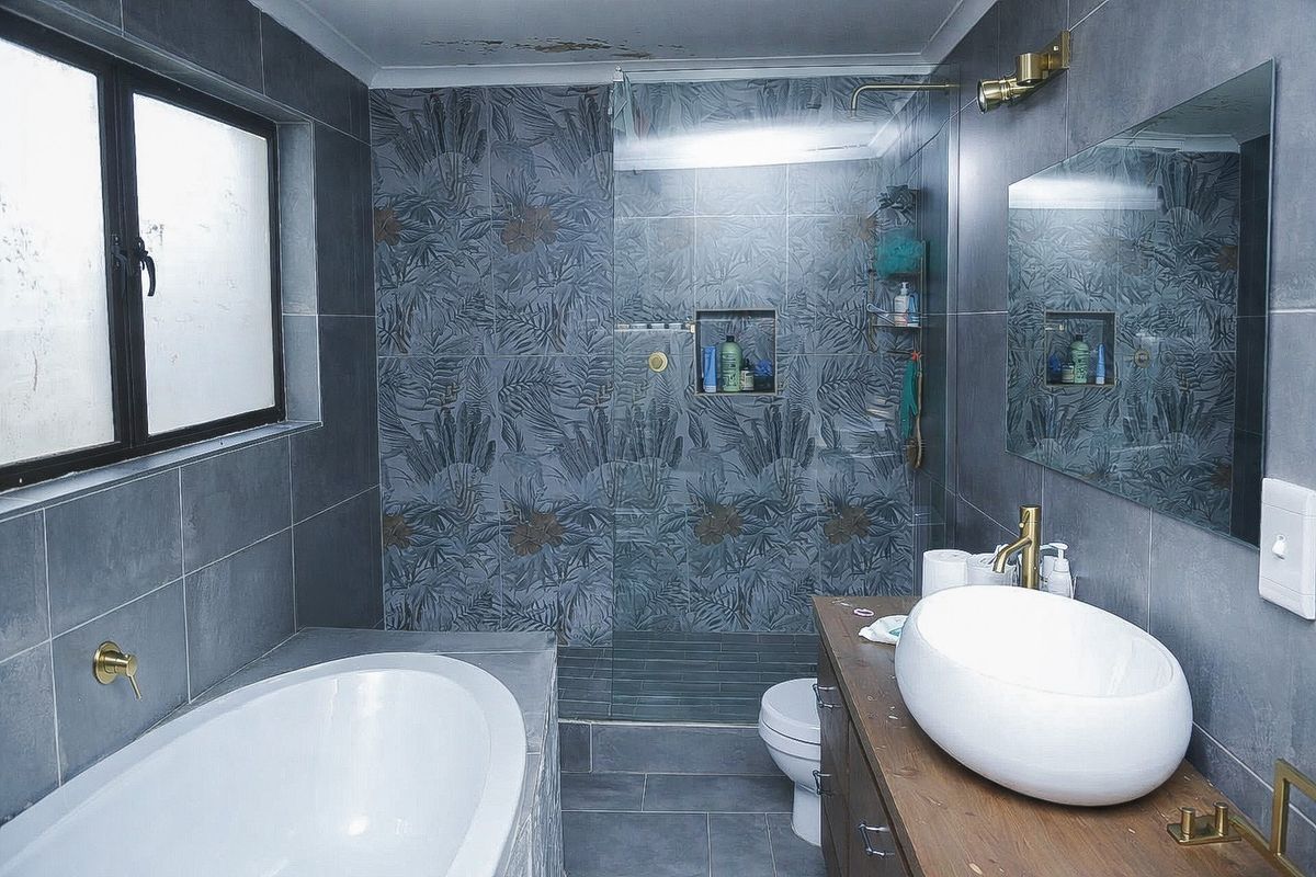 Modern bathroom featuring a freestanding bathtub, walk-in shower with patterned tile accents, vessel sink vanity, and brass fixtures.